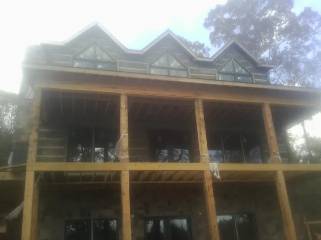 Dormers and porch framing on a large log home under construction — Roof Coating work by our crew in Hugo