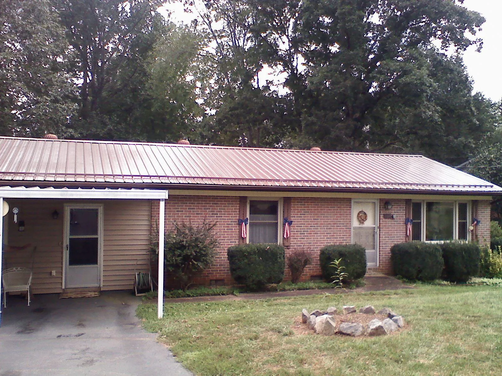 Bronze metal roof and carport on a brick ranch home — Roof Repair work by our crew in Hugo